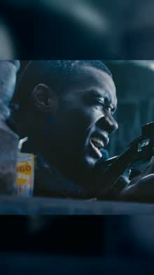 A man in glasses shouting as he grips a control inside a vehicle