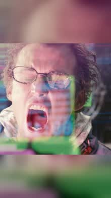 A man in glasses shouting amid green glitch light